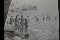 Swimmers on beach and long concrete pier